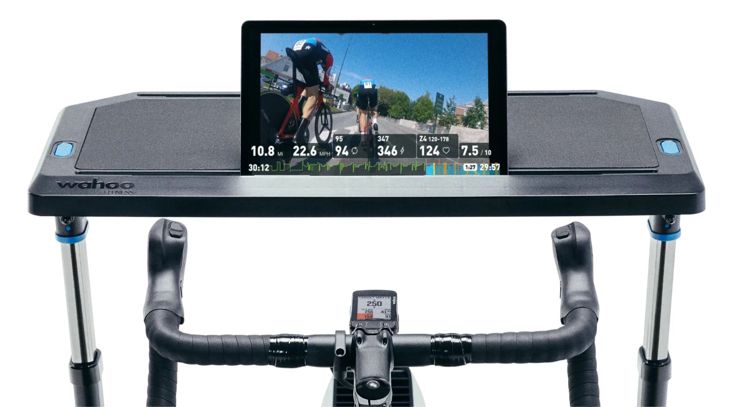 A tablet displaying a cycling workout video, resting on a Wahoo desk accessory attached to an indoor cycling setup